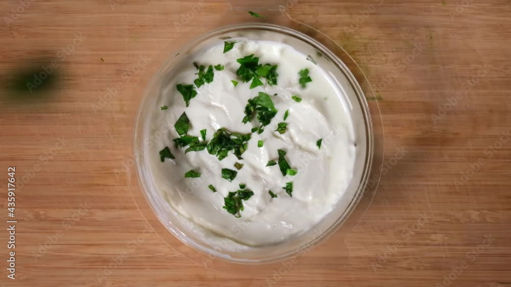 Slow motion of chopped fresh greens falling into a bowl of yoghurt, point of view shot, top view. Slow motion of chopped fresh greens falling into a bowl of yoghurt, point of view shot, top view.
