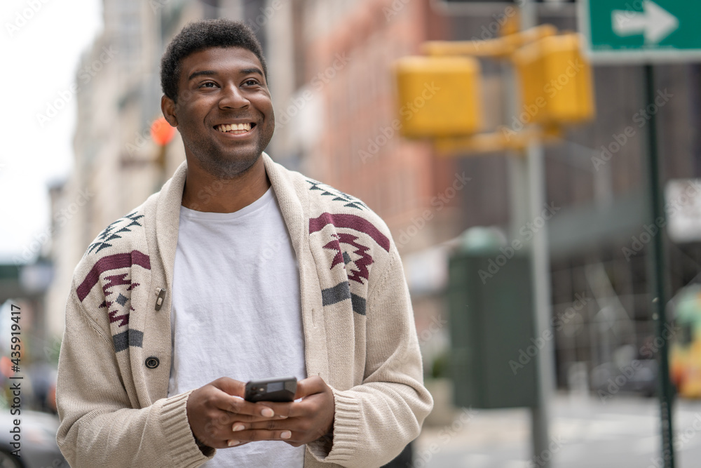 Young black man in city walking street texting on cellphone Young black man in city walking street texting on cellphone