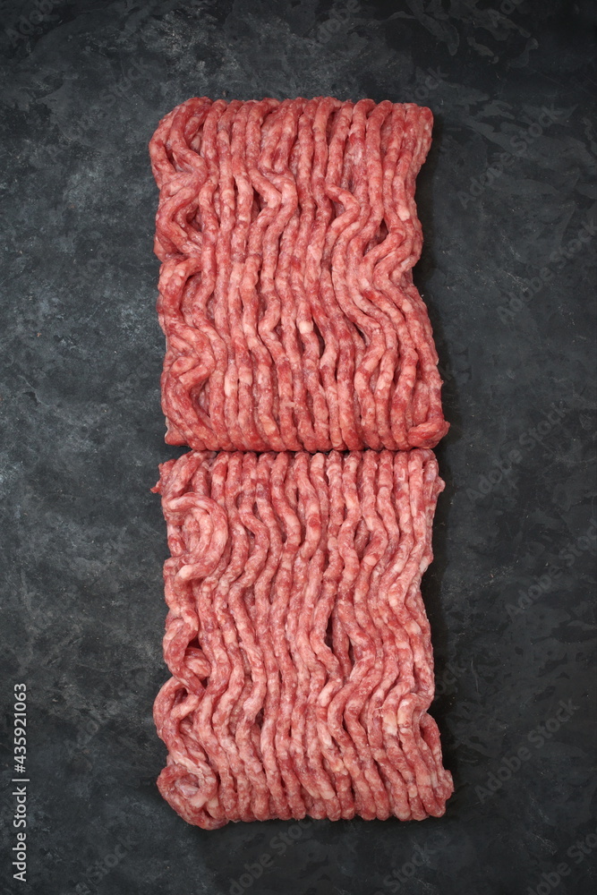 Fototapeta premium Raw Minced Meat On Black Vintage Background. Top View Of Fresh Ground Beef Isolated On Black Background. Uncooked Minced Mixed Beef And Pork Meat.
