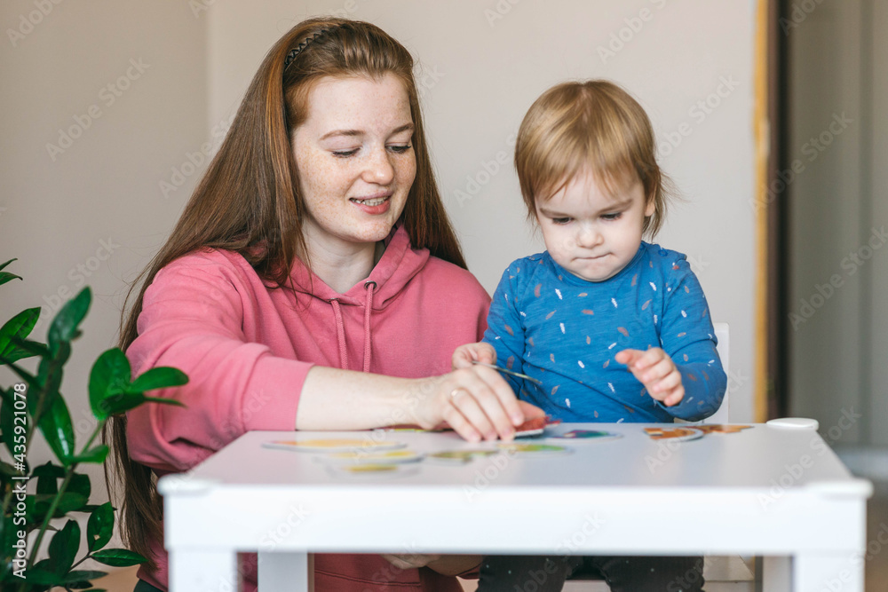 Young mother and one and a half year old girl collects puzzles. Psychomotor skills and the development of logical thinking Young mother and one and a half year old girl collects puzzles. Psychomotor skills and the development of logical thinking