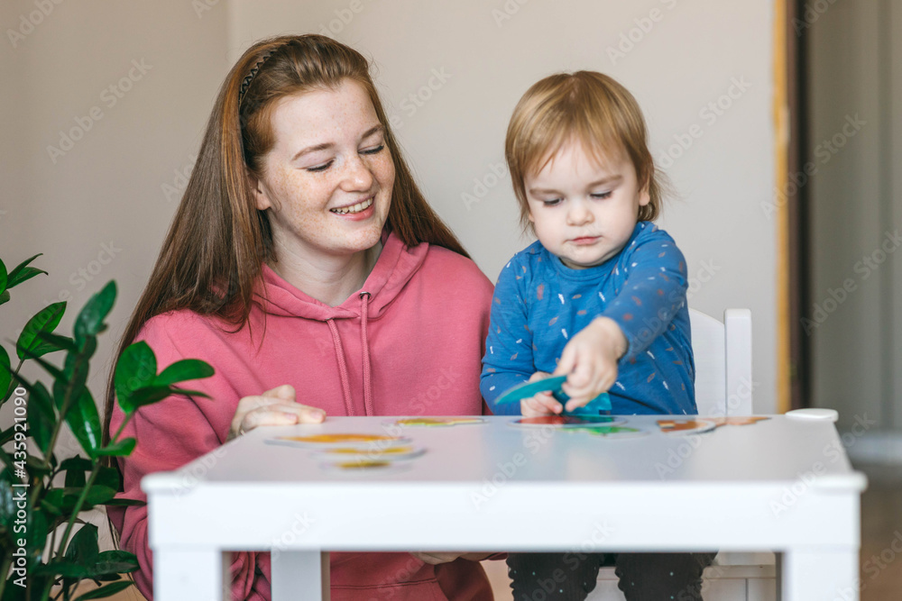 Young mother and one and a half year old girl collects puzzles. Psychomotor skills and the development of logical thinking Young mother and one and a half year old girl collects puzzles. Psychomotor skills and the development of logical thinking