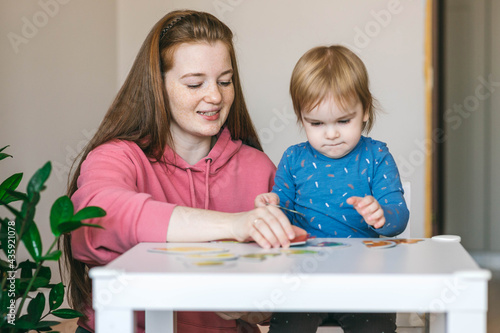 Young mother and one and a half year old girl collects puzzles. Psychomotor skills and the development of logical thinking	