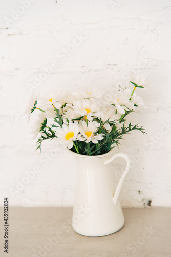 bouquet of daisies flowers in a white rustic vase on the table, vertical photo.
