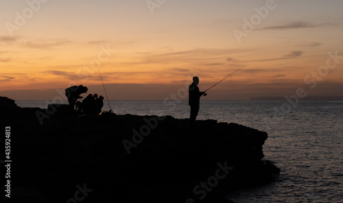 Silhouette of a fisherman with another group behind him at sunset