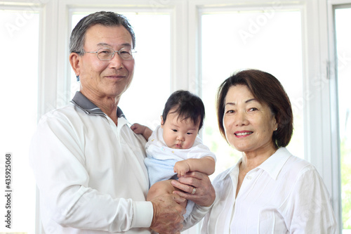 Japanese senior couple hugging their grandchildren and smiling at the camera