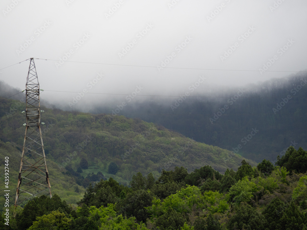 Power line support with wires in the clouds on the green mountains of the Krasnodar Territory, Novorossiysk, Russia. Scenery of rural, suburban areas. Power line support with wires in the clouds on the green mountains of the Krasnodar Territory, Novorossiysk, Russia. Scenery of rural, suburban areas.