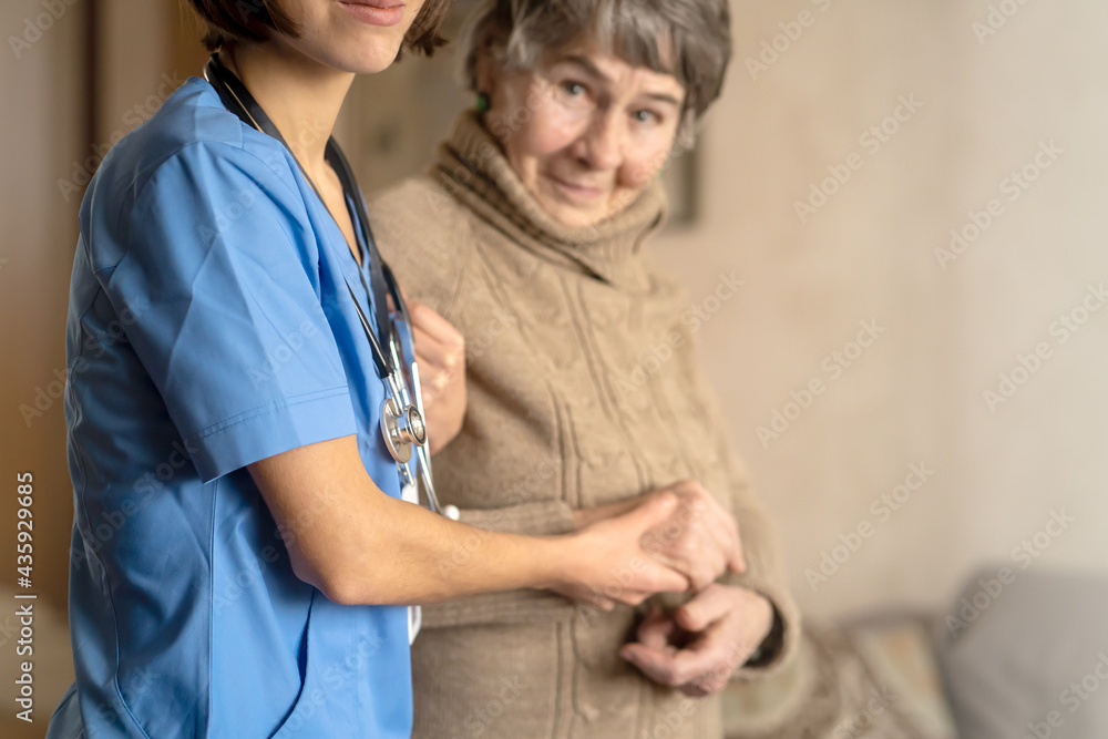 Obraz premium A young nurse shows care and professionalism in relation to an elderly woman, a pensioner. Young woman doctor visits the patient at home and conducts medical therapy