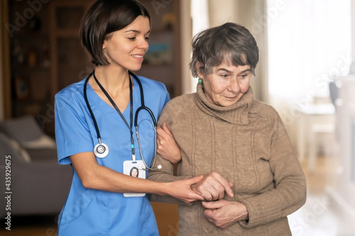 A young nurse shows care and professionalism in relation to an elderly woman, a pensioner. Young woman doctor visits the patient at home and conducts medical therapy