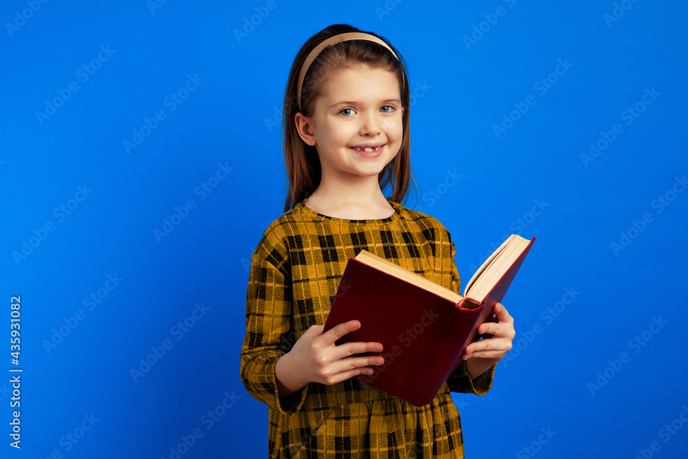 Happy child smiling and holding a book against blue background Happy child smiling and holding a book against blue background
