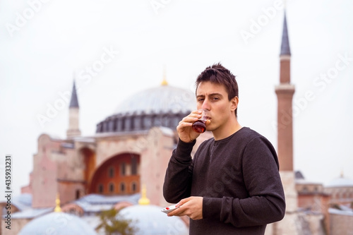 Photography A young man drinks traditional Turkish tea on the background of the Hagia Sophia mosque