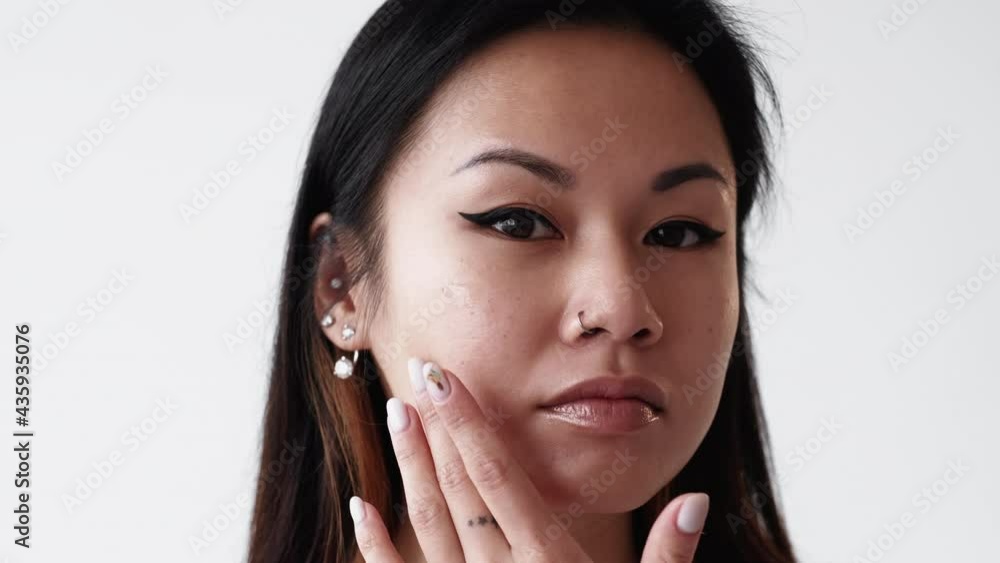 Facial care. Female beauty procedure. Anti-aging cosmetic. Skin treatment. Pretty asian woman with black eyeliner makeup applying hyaluronic acid on face isolated white. Facial care. Female beauty procedure. Anti-aging cosmetic. Skin treatment. Pretty asian woman with black eyeliner makeup applying hyaluronic acid on face isolated white.