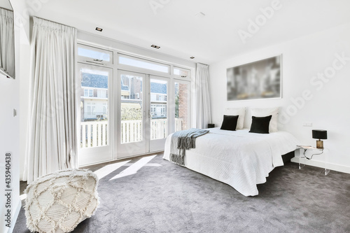 Tablou pe pânză Interior of modern spacious master bedroom with big bed under city photo and gra