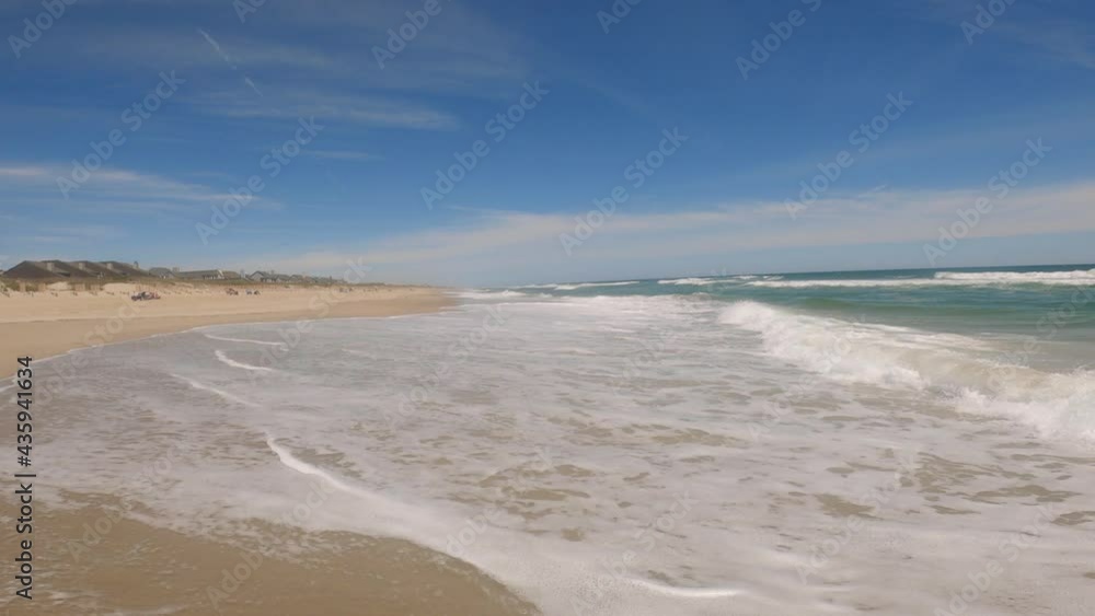 Beautiful sunny day on a calm pristine beach with blue skies in North Carolina in the Outer Banks in Nags Head during early summer Beautiful sunny day on a calm pristine beach with blue skies in North Carolina in the Outer Banks in Nags Head during early summer