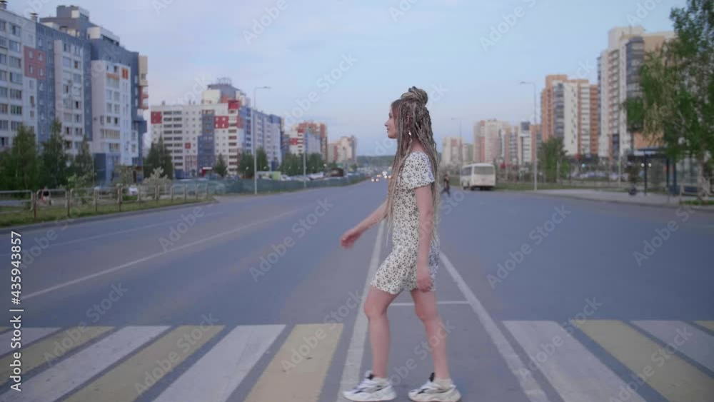 A girl with dreadlocks walking down a road