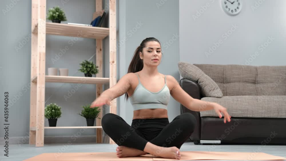 Smiling flexible woman sitting in lotus position warming up stretching spine practicing morning yoga Smiling flexible woman sitting in lotus position warming up stretching spine practicing morning yoga