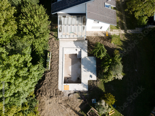 Drone shot of pool construction site in a garden, earth around the pool is already backfilled