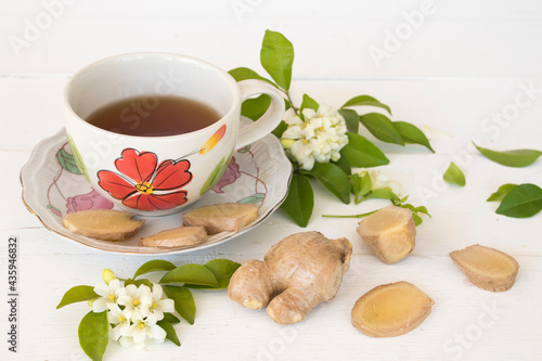 hot ginger water herbal healthy drinks health care for cough sore with flowers arrangement flat lay style on background wooden white