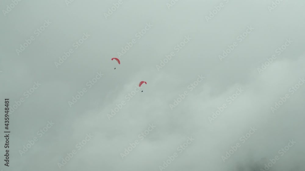 Extreme paragliders flying against rain clouds in extremely bad flying conditions Extreme paragliders flying against rain clouds in extremely bad flying conditions