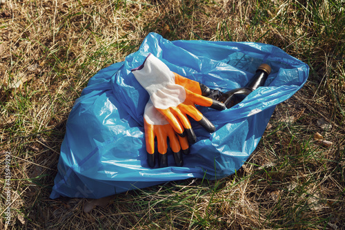 A volunteer and eco activist collects garbage in bags, in the forest, close-up. Recycling of plastic waste, environmental protection. Protecting the planet from debris. Ecology concept