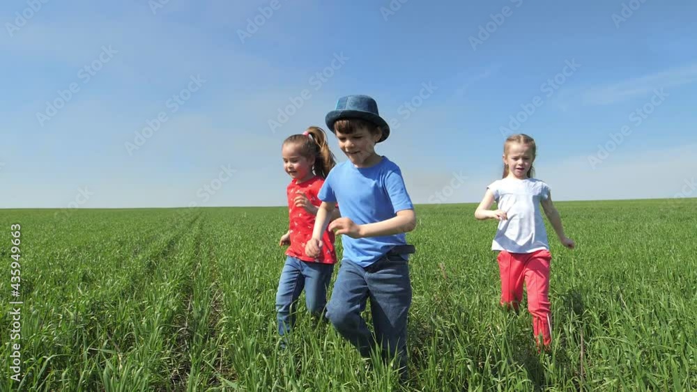Happy children, boys and girls, run merrily on the green beautiful floor. Children play catch-up in the park. The concept of children's happiness. Slow motion Happy children, boys and girls, run merrily on the green beautiful floor. Children play catch-up in the park. The concept of children's happiness. Slow motion