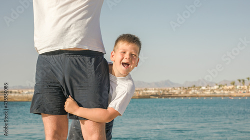 Fototapeta Naklejka Na Ścianę i Meble -  Father and  son  spending time together sea vacation. Young man, little boy walking beach Fathers day. Family with one child. Happy childhood with daddy.