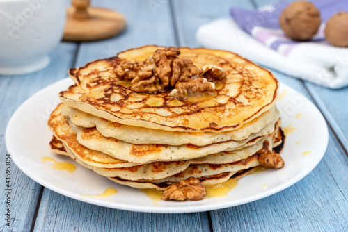 Small pancakes, honey and walnuts on a wooden table