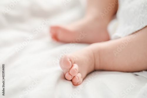 Legs of cute little baby lying on bed, closeup