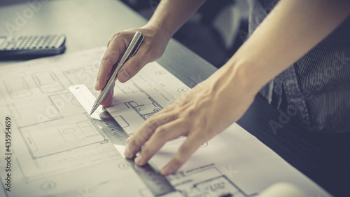 Engineer and Architect concept, Man uses a ruler to measure the floor plan on the blueprint, Building architecture design work, Construction design project under environmental conservation conditions.