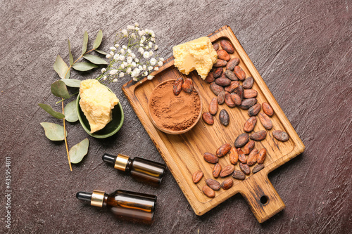 Composition with cocoa butter, beans, powder and essential oil on dark background