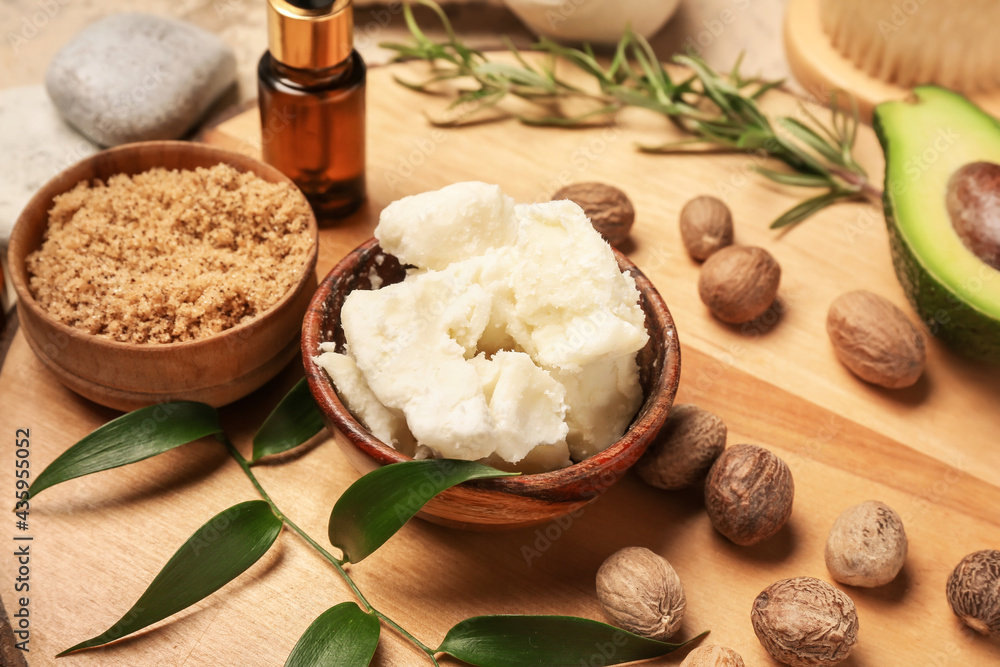 Fototapeta premium Bowl with shea butter, nuts and scrub on table