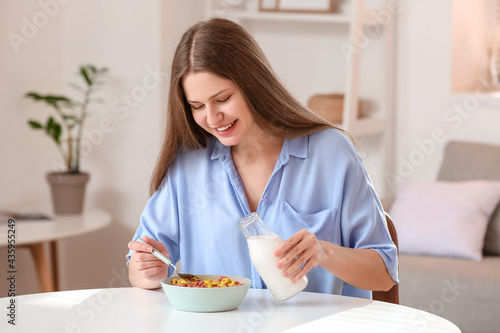 Young woman pouring milk in...