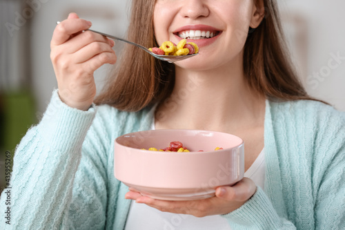 Beautiful young woman eating cornflakes at home, closeup