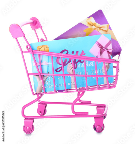 Shopping cart with gift cards on white background photo