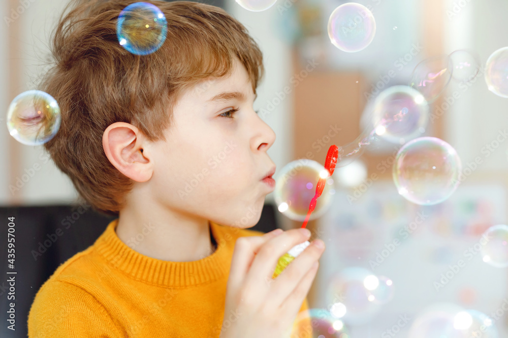 Happy little school boy playing with soap bubbles at home. Kid having fun. Child playing at school, making experiment Happy little school boy playing with soap bubbles at home. Kid having fun. Child playing at school, making experiment