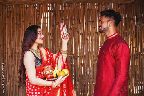 Indian woman celebrating Karva Chauth by looking at her husband after looking at the moon at night photo