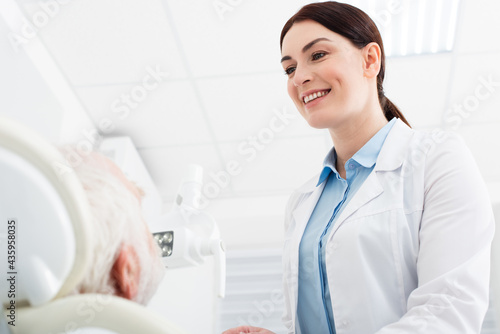 smiling dentist looking at senior patient in dental chair. © LIGHTFIELD STUDIOS