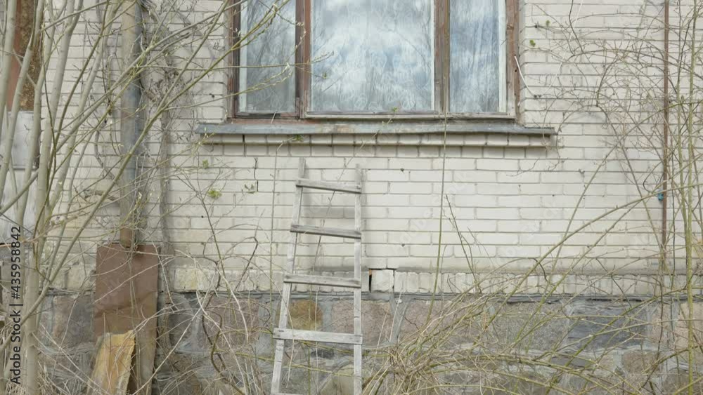 The wooden ladder on the side of the wall of the ruined abandoned house The wooden ladder on the side of the wall of the ruined abandoned house
