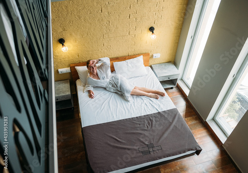 Woman in white robe on bed in hotel 