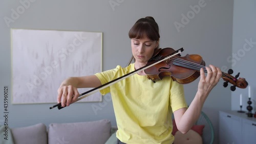 Attractive Refined Violinist Is Tuning a Violin. Tune the Strings. beautiful Woman Is Practising Violin  photo