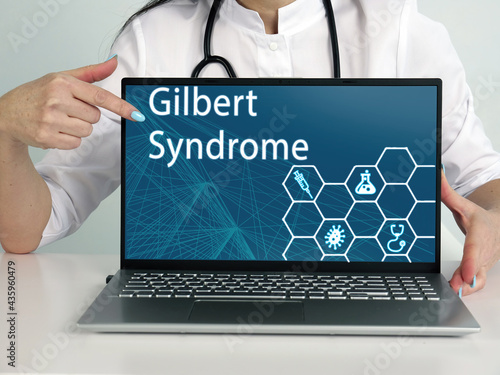  Gilbert Syndrome inscription on the screen. Close up male hands holding black laptop. photo