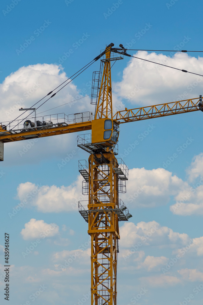 The top of a construction crane on a blue sky background with white clouds The top of a construction crane on a blue sky background with white clouds