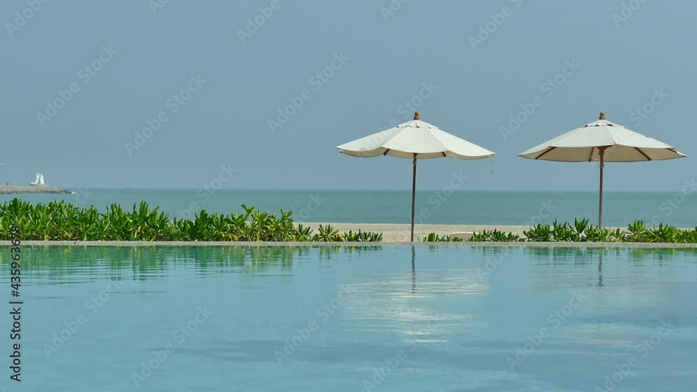 Swimming pool with umbrella and chair on sea view background
Swimming pool with umbrella and chair on sea view background