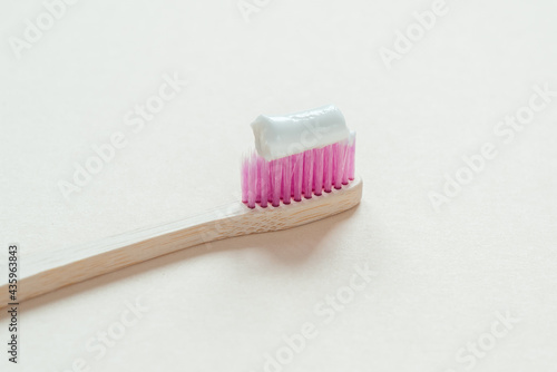 Pink bamboo toothbrush with tooth paste on it close-up, dental care with zero waste concept, sustainable lifestyle