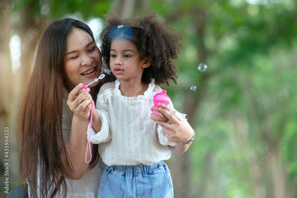 Little girl and mother enjoyed playing blowing bubbles in the park. Little girl and mother enjoyed playing blowing bubbles in the park.