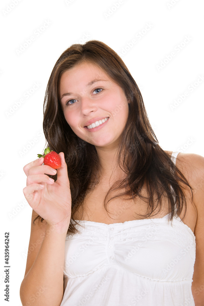 Cute smiling girl holding a red strawberry in her hand, isolated in front of white background Cute smiling girl holding a red strawberry in her hand, isolated in front of white background