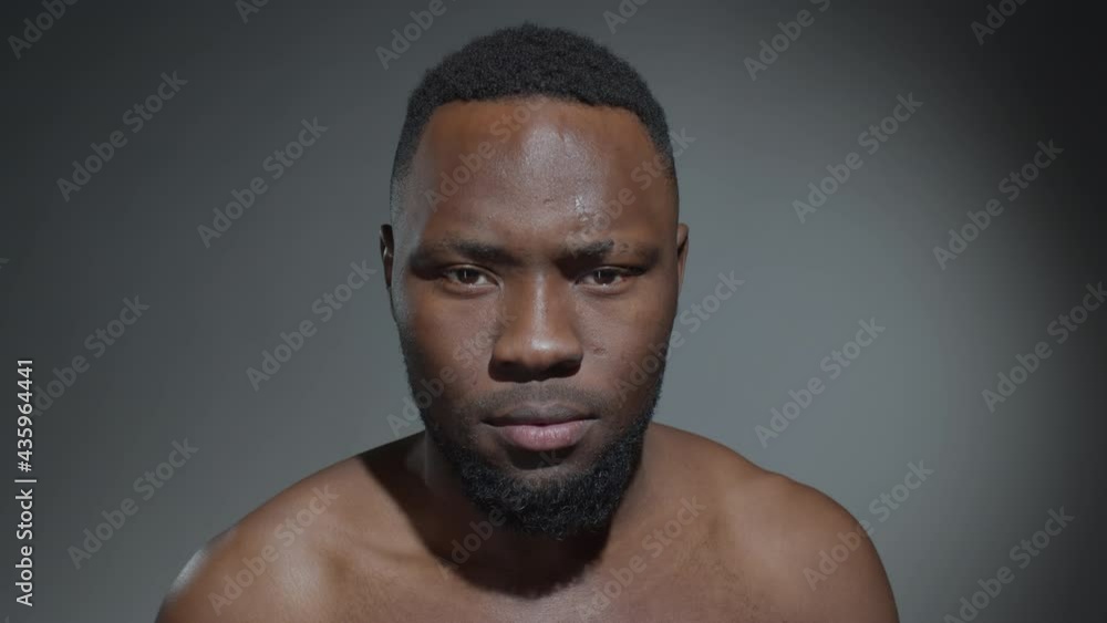 Studio portrait of young shirtless Afro-American man tilting up his head and looking at camera Studio portrait of young shirtless Afro-American man tilting up his head and looking at camera