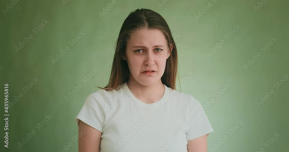 Young woman cries with offence posing for camera on green Young woman cries with offence posing for camera on green
