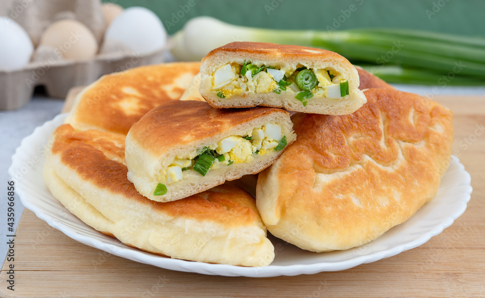 Tortilla dough stuffed with green onions and egg on a white plate. Tortilla dough stuffed with green onions and egg on a white plate.