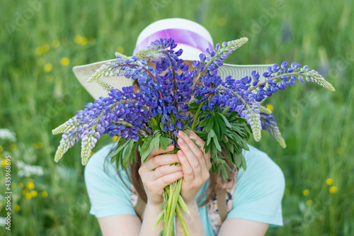 Girl with lupins covered her face with flowers