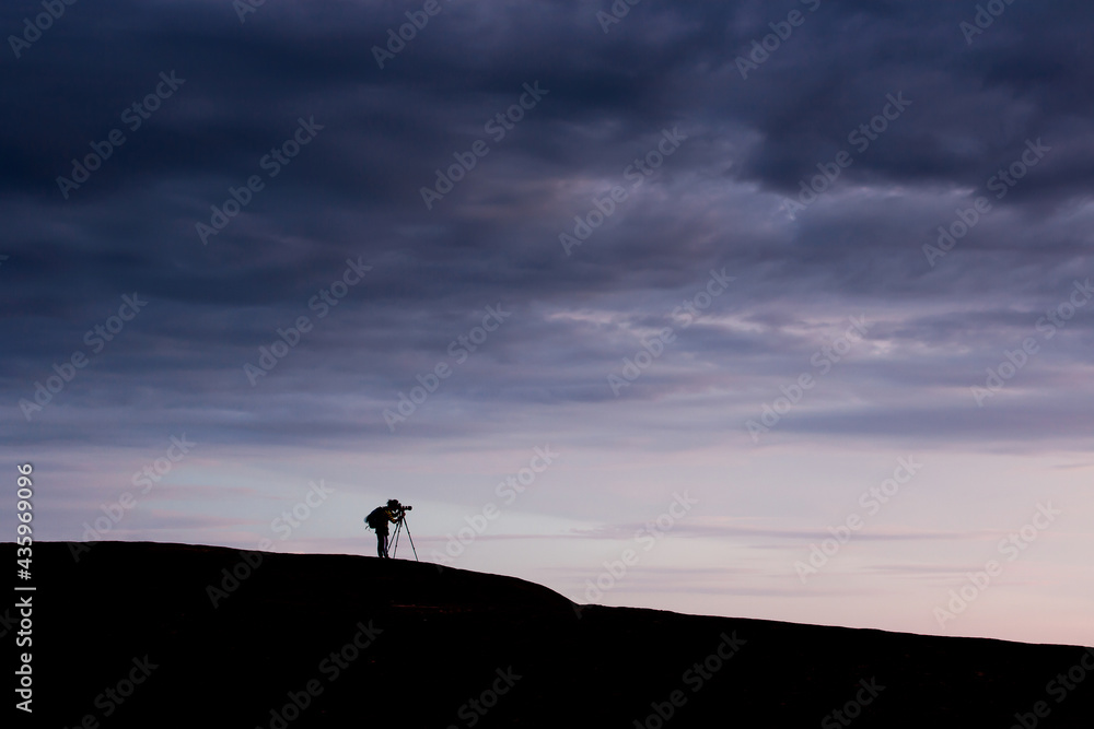 Young man taking pictures on the mountain peak.
